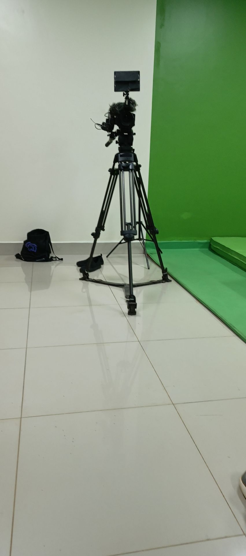 A camera on a tripod facing the green-screen stage